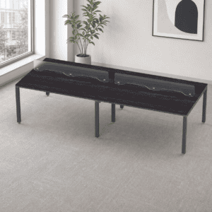 Mesa de oficina moderna con divisores de vidrio y estructura metálica para espacios de trabajo.