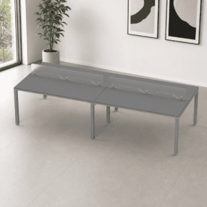 Mesa de oficina moderna con división de vidrio y espacio para trabajo colaborativo.